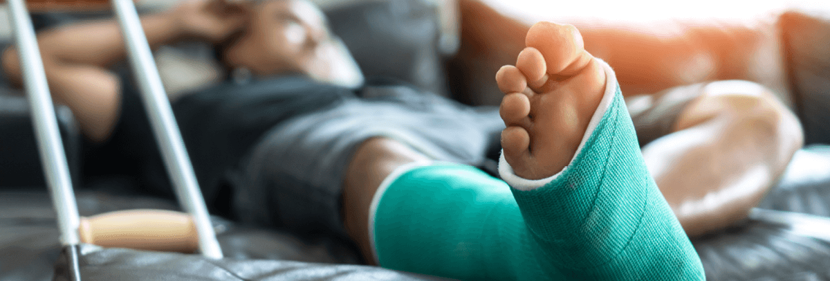 man lying on couch with foot in cast